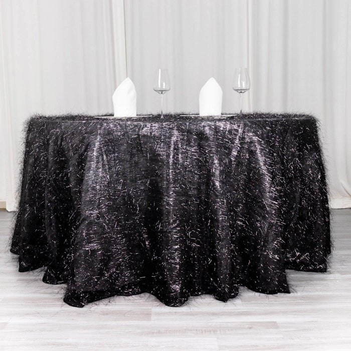 Black textured tablecloth with elegant white napkins and glasses.