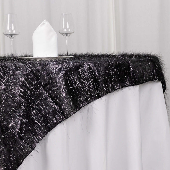 Black and silver table runner with fringe on a white tablecloth.