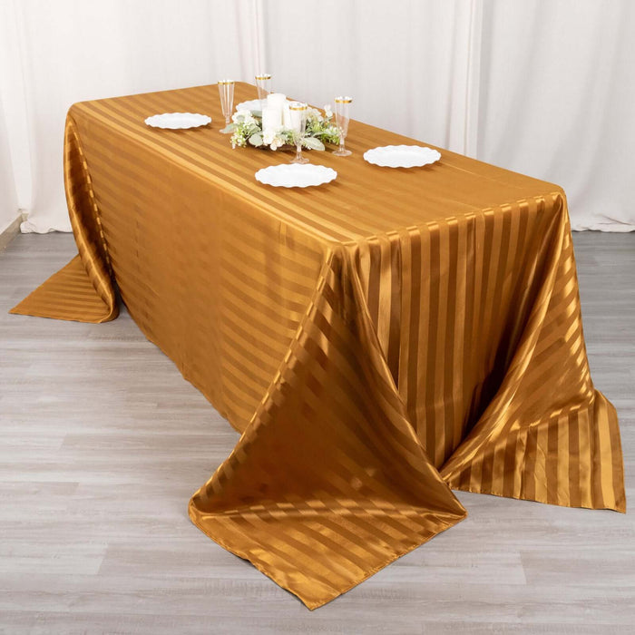 Gold striped tablecloth on a wooden table with decorative plates and centerpieces.