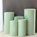Green cylindrical pedestals in various sizes against a gray wall.