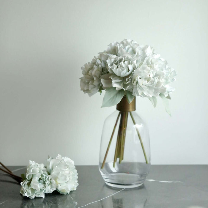 White floral arrangement in a glass vase with a gold accent.