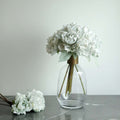 White floral arrangement in a glass vase with a gold accent.