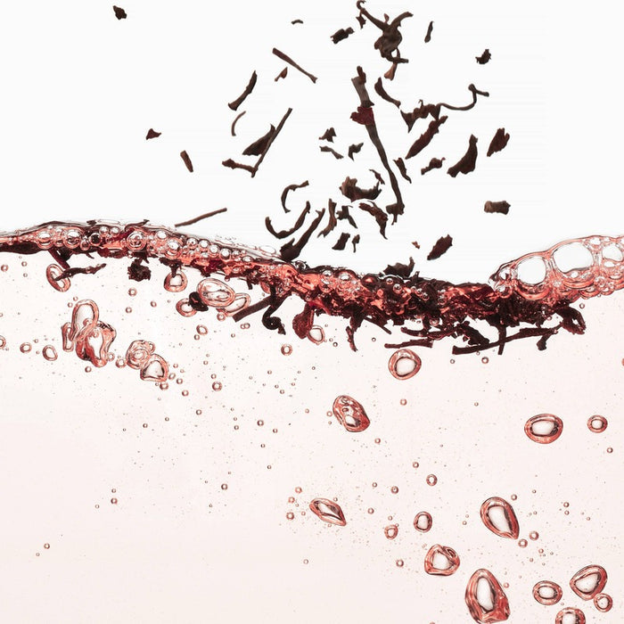 VOESH Black Tea & Rosé Hand Balm artistic product display with liquid and particles