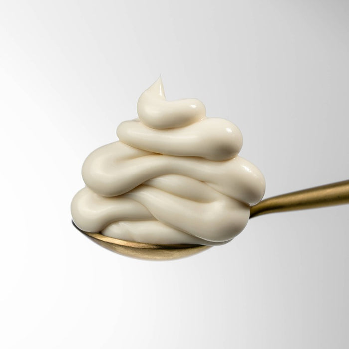 VOESH Black Tea & Rosé Hand Balm creamy texture on gold spoon against white background